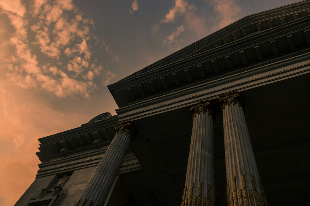 Classical government building facade with columns against a dramatic sky